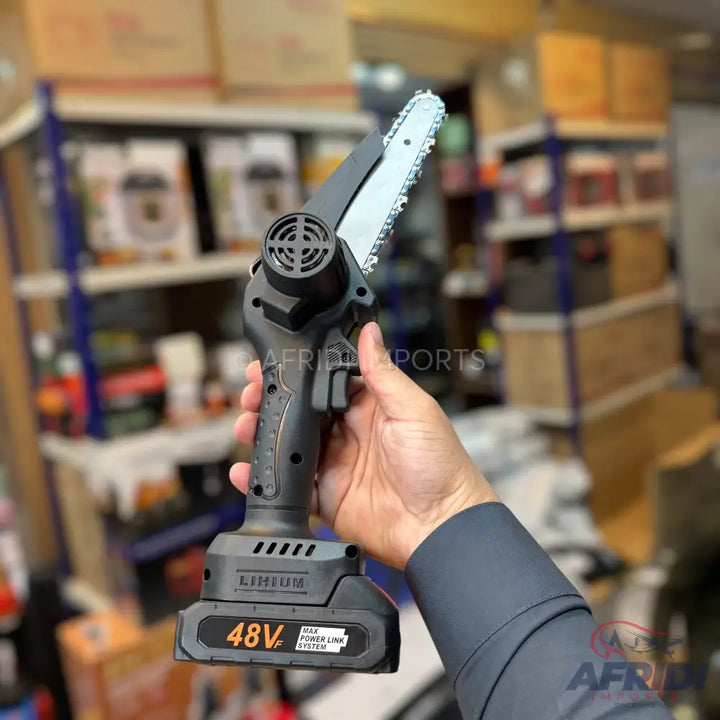 A black, handheld, cordless mini chainsaw with an orange 48V battery attached.
