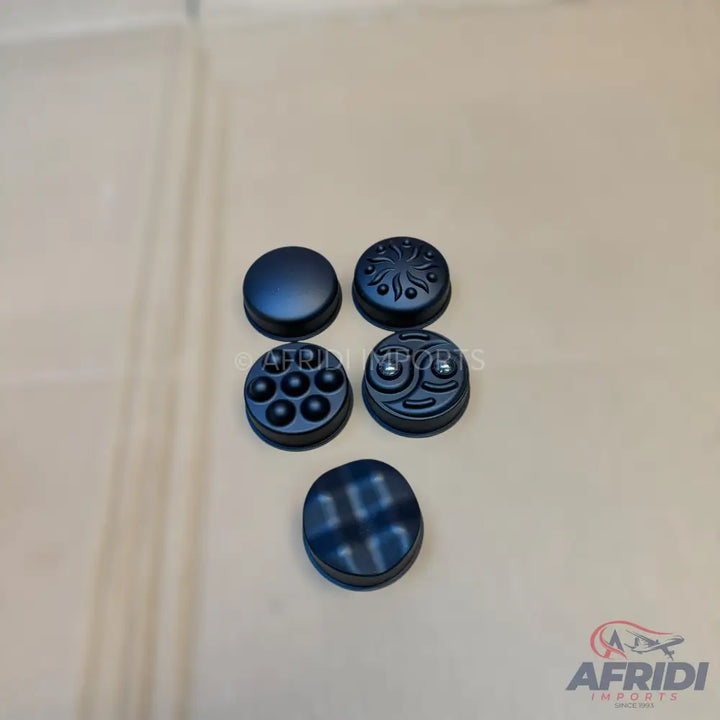 A set of five dark-colored, textured, interchangeable controller thumb grips.