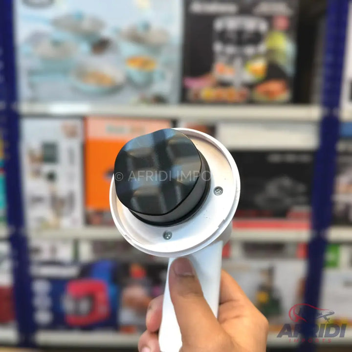 A handheld white device with a black, rounded, square-shaped top.