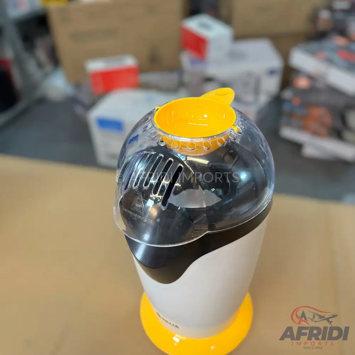 A white and black popcorn maker with a clear top and yellow accents.