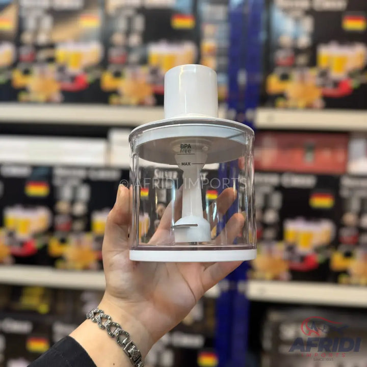 A handheld, clear plastic food chopper or blender attachment with a white lid and blade assembly.