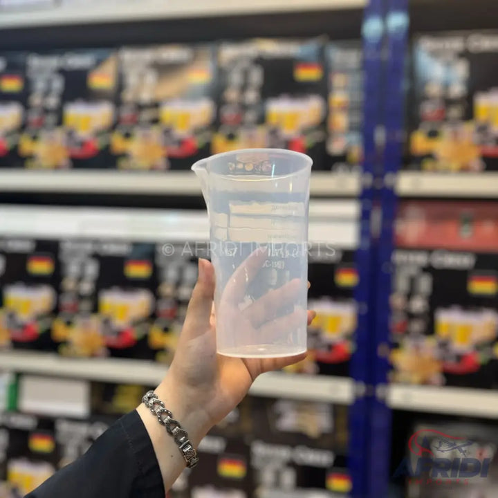 A clear, plastic measuring beaker with a pouring spout and measurement markings.