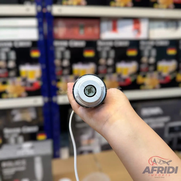 A hand holding a white and black blender base with a power cord.