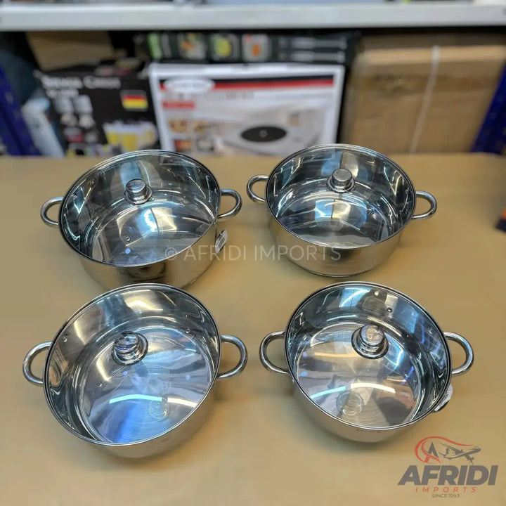 A set of four stainless steel cooking pots with clear glass lids.