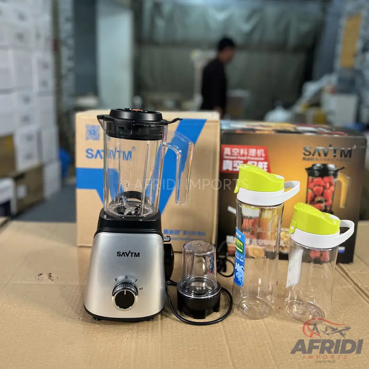 A silver electric blender with a transparent pitcher and an additional small grinding cup, accompanied by two clear plastic bottles with bright green flip-top lids.