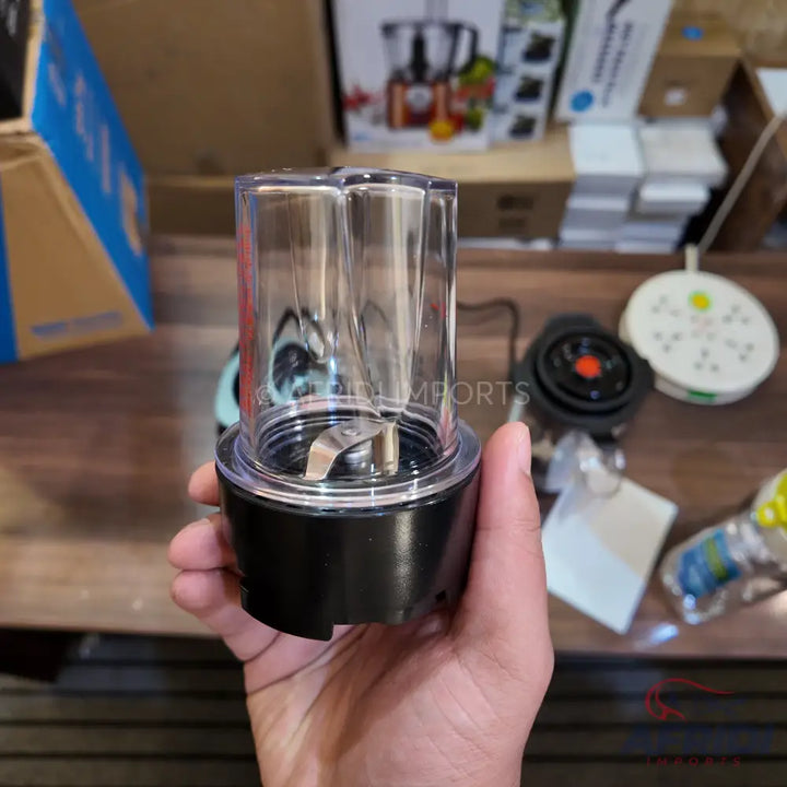 A clear plastic blender cup with a black base and a single blade attached.