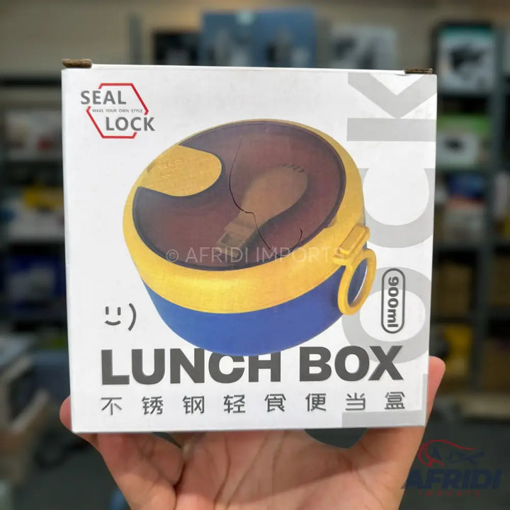 A packaged blue and yellow round lunch box with a clear lid and a spoon.