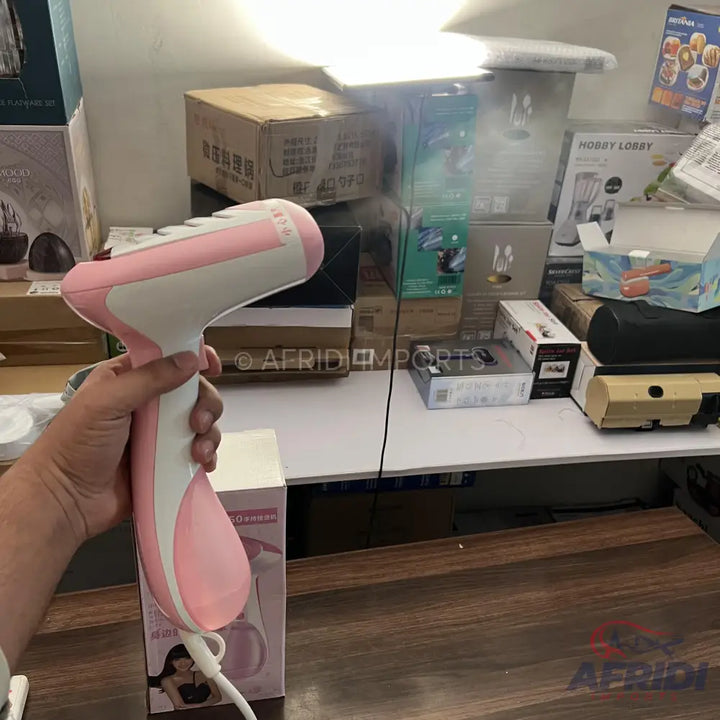 Pink and white handheld garment steamer.