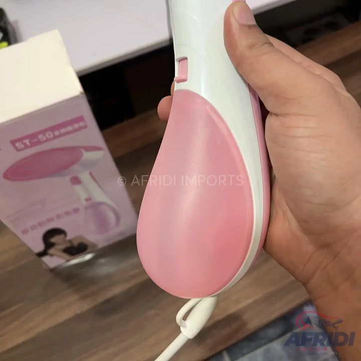 Pink and white handheld garment steamer.