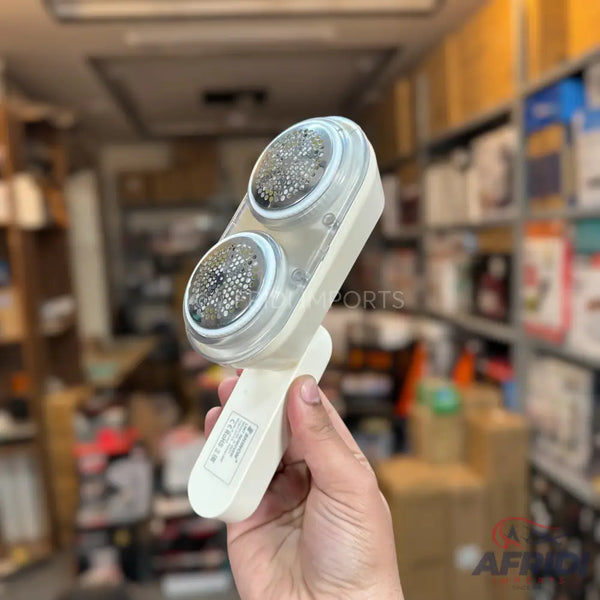 A white, handheld lint remover with two circular shaving heads.