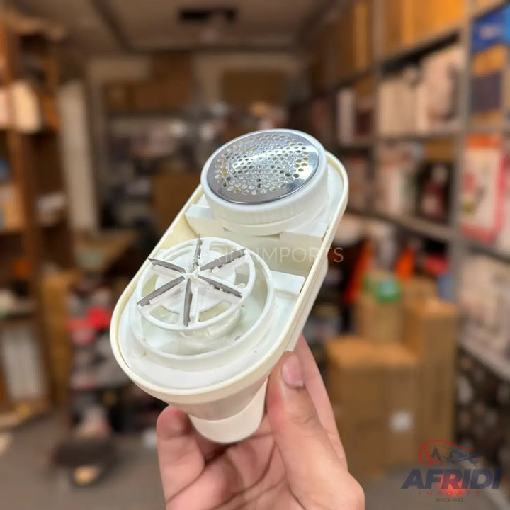 White lint remover with a metal mesh head and internal blades.