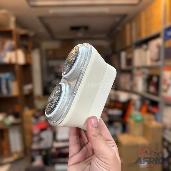 Handheld lint remover with two circular shaving heads.
