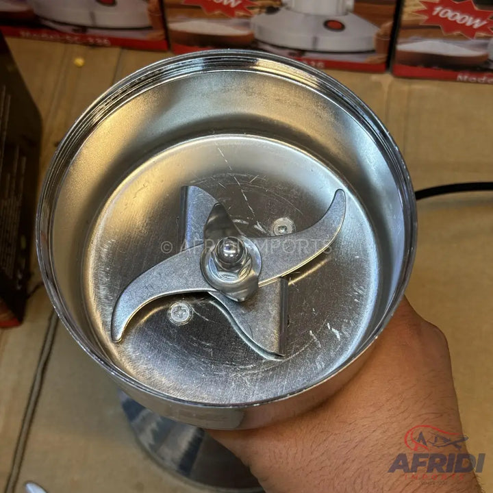 A stainless steel spice grinder with a three-pronged blade.
