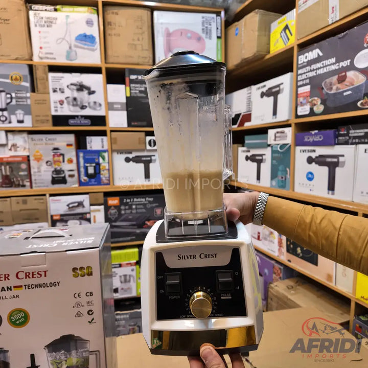 White and gold blender with a clear pitcher containing a light brown liquid.