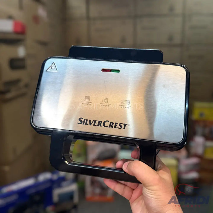A stainless steel sandwich maker with indicator lights.
