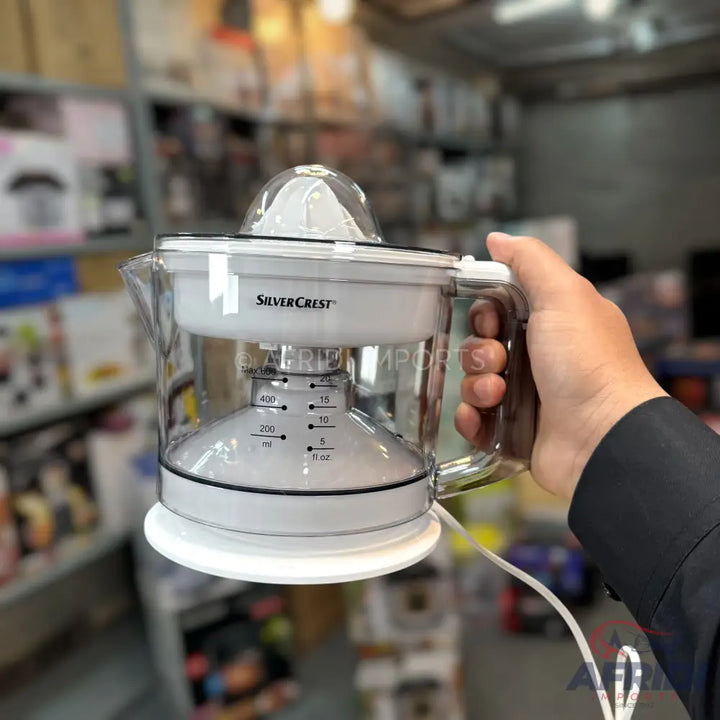 A clear and white electric citrus juicer with measurement markings.