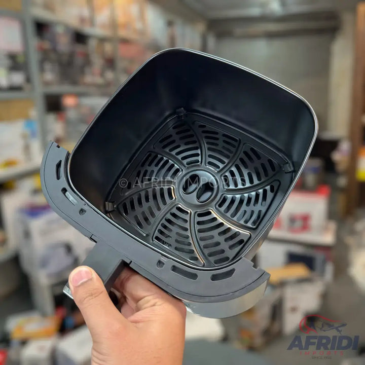 An empty, dark gray air fryer basket with a removable perforated crisping plate.