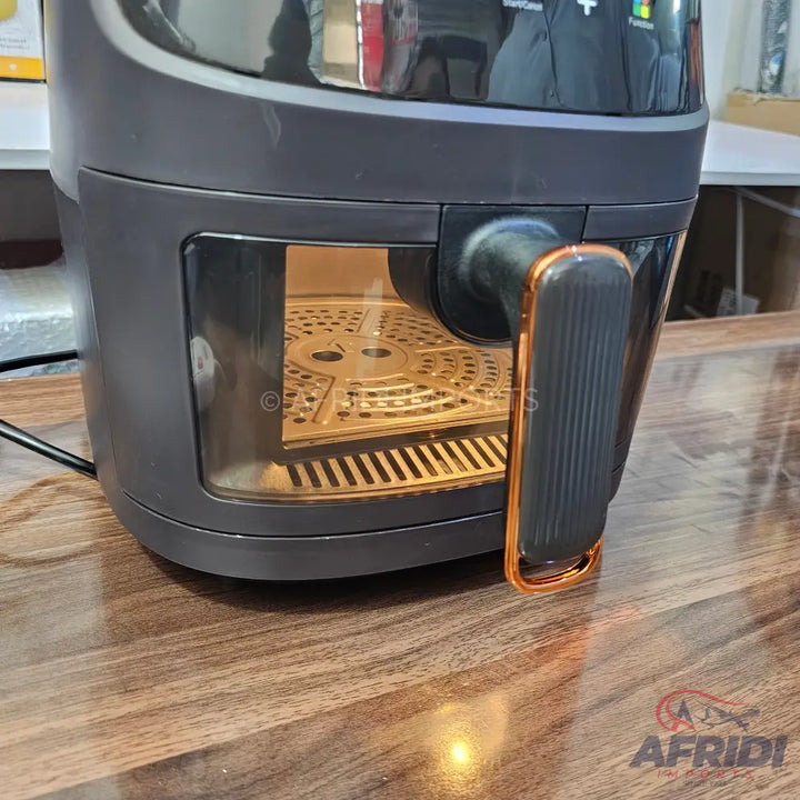 Dark gray air fryer with a clear window and a copper-accented handle.