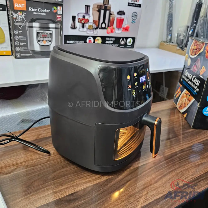 Black digital air fryer with a clear window and a gold handle.