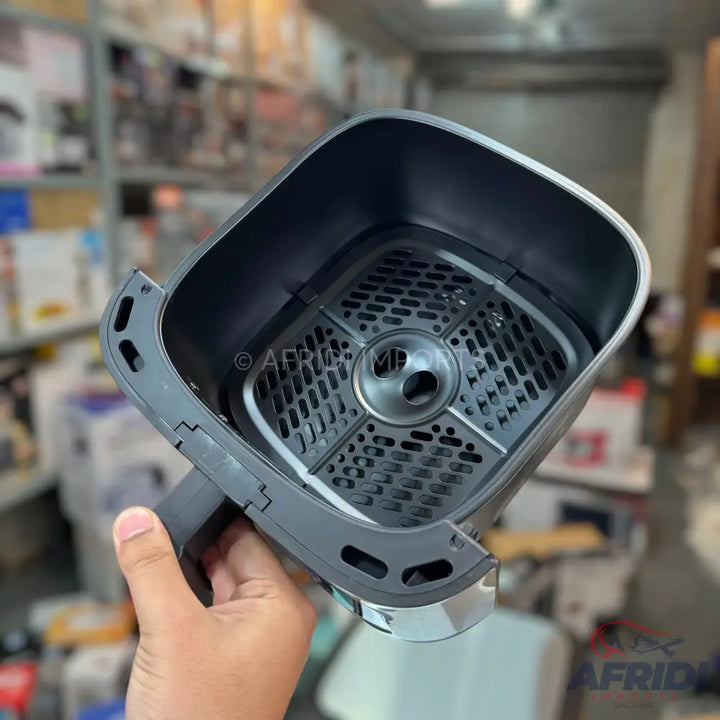 Empty black air fryer basket with a perforated insert.