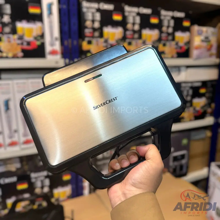 A silver and black sandwich maker held in a hand.