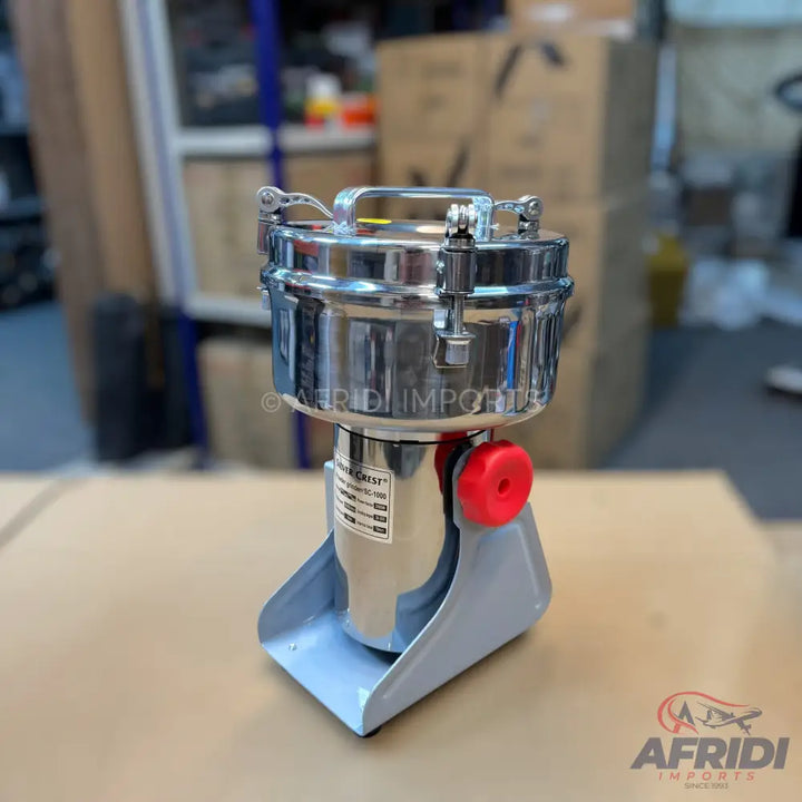 Stainless steel electric grain grinder with a red power knob.