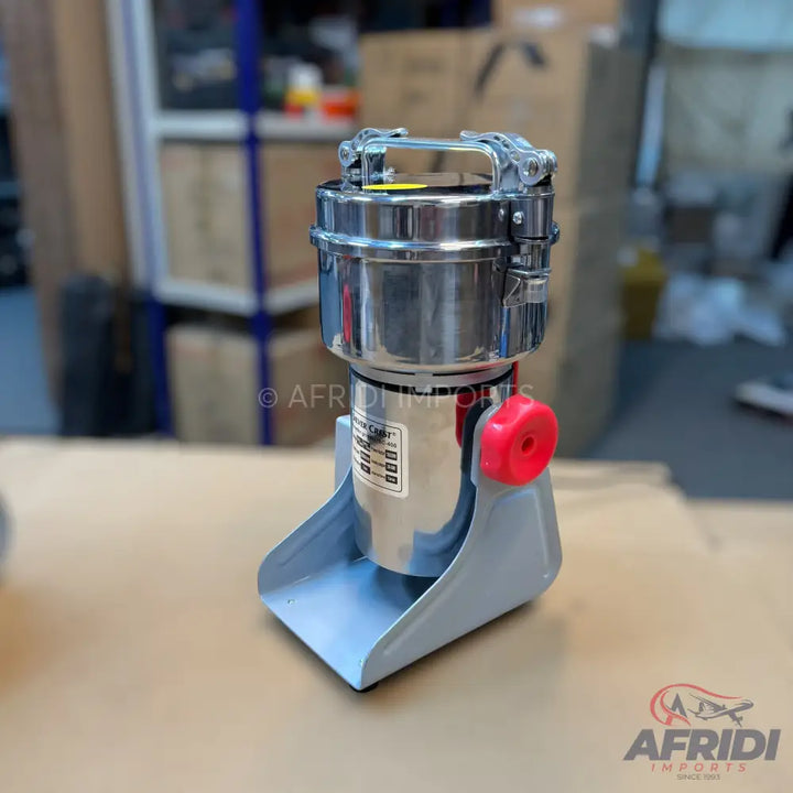 A stainless steel commercial spice grinder with a red knob and a light blue base.