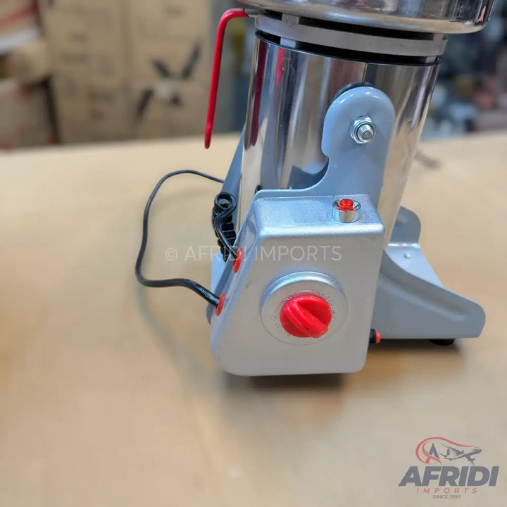 Silver-colored electric food grinder with red controls.