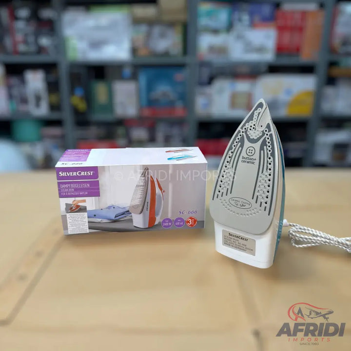 A white and orange steam iron with a ceramic soleplate, packaged in its box, is displayed.