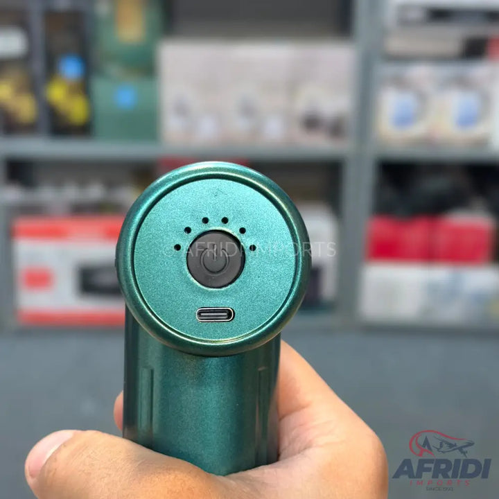 A handheld teal massage gun with a power button, four indicator lights, and a USB-C charging port.