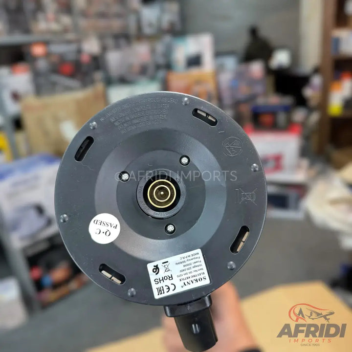 The base of a black electric kettle with a central power connector and various regulatory labels.