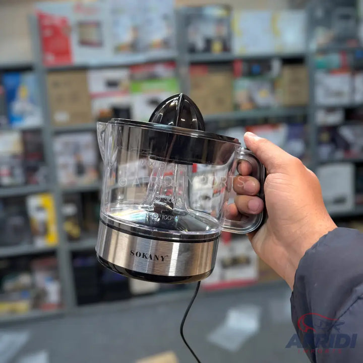 A clear plastic and stainless steel electric citrus juicer with a black reamer.