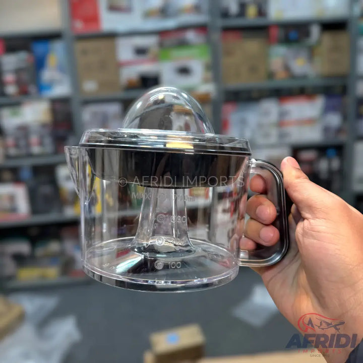 A clear plastic manual citrus juicer with a dark grey top.
