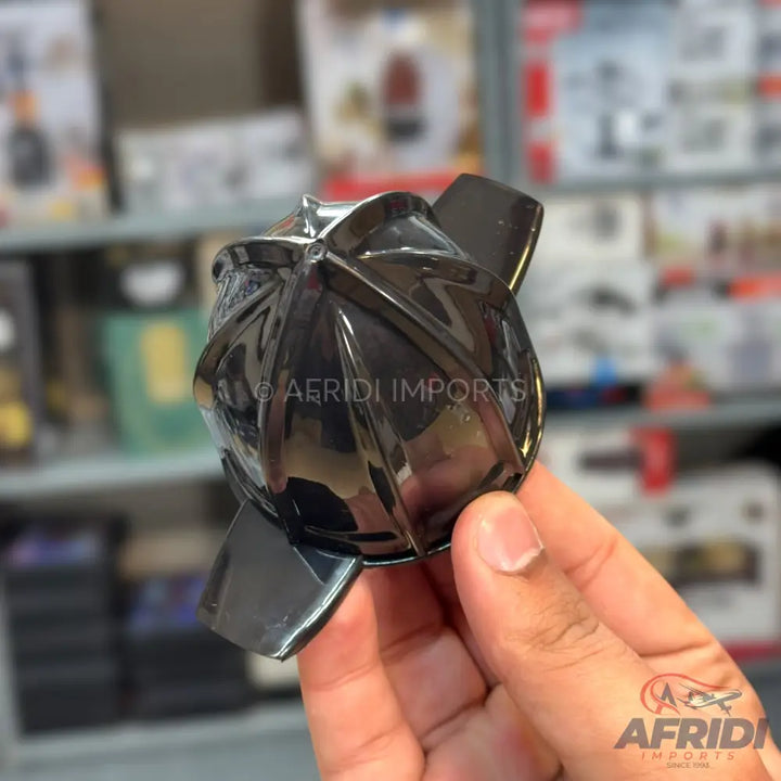A black, glossy, multi-faceted plastic juicer reamer with four fins.
