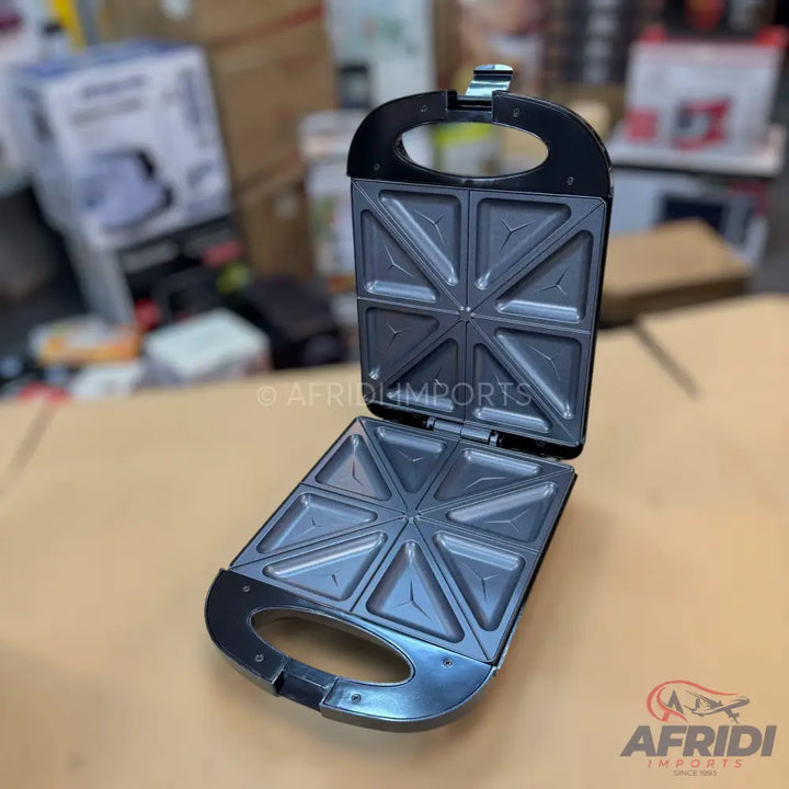 An open, black sandwich maker with triangular plates for four sandwiches.