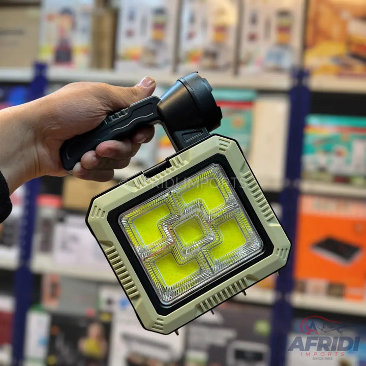 A handheld, dual-purpose LED work light with a spotlight and a multi-panel floodlight.
