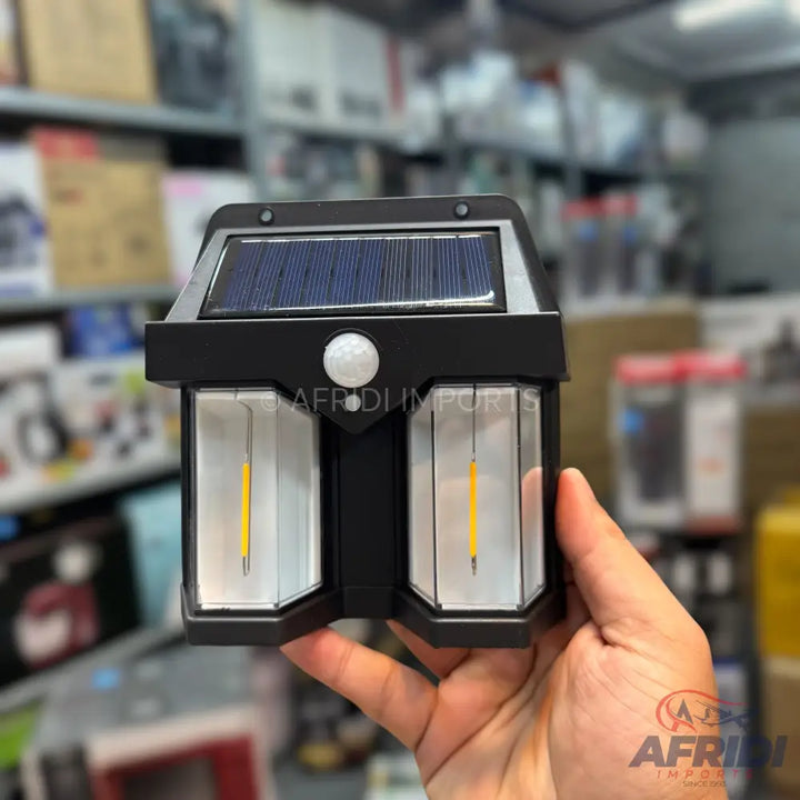 Black solar-powered outdoor light with a motion sensor and two downward-facing LED panels.