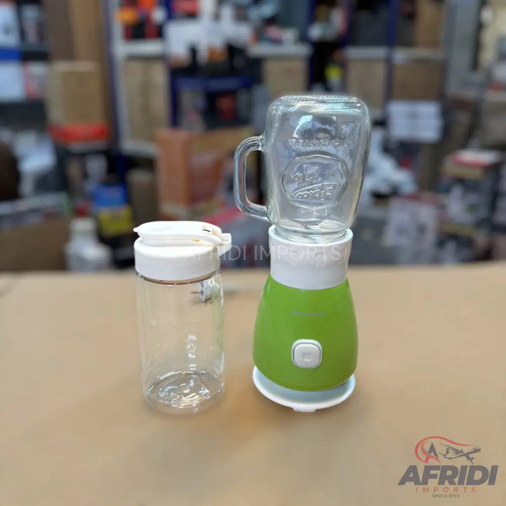 A green and white personal blender with a glass jar and an additional clear plastic bottle.