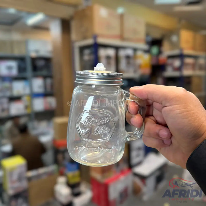 Clear glass mason jar mug with a silver lid and a white stopper.