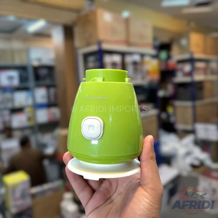 A vibrant green, compact food chopper with a white button and base.