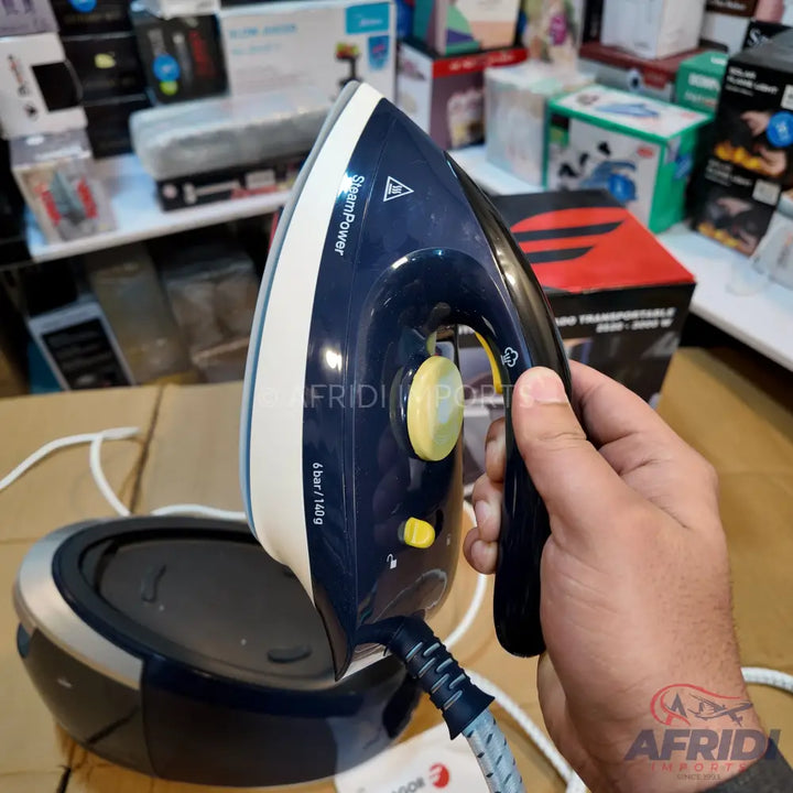 Dark blue and white steam iron with a yellow dial and buttons, connected to a base unit.