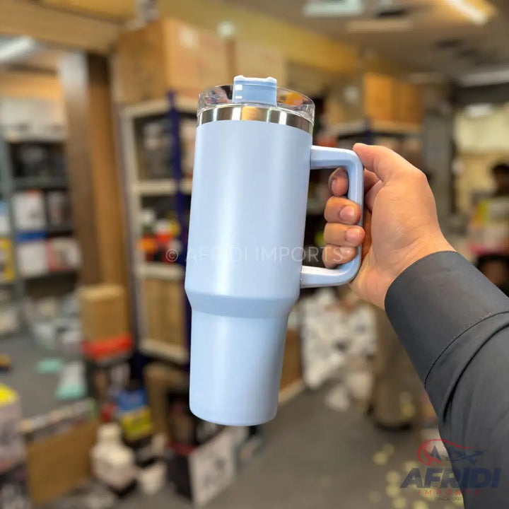 Light blue insulated travel mug with a handle and clear lid.
