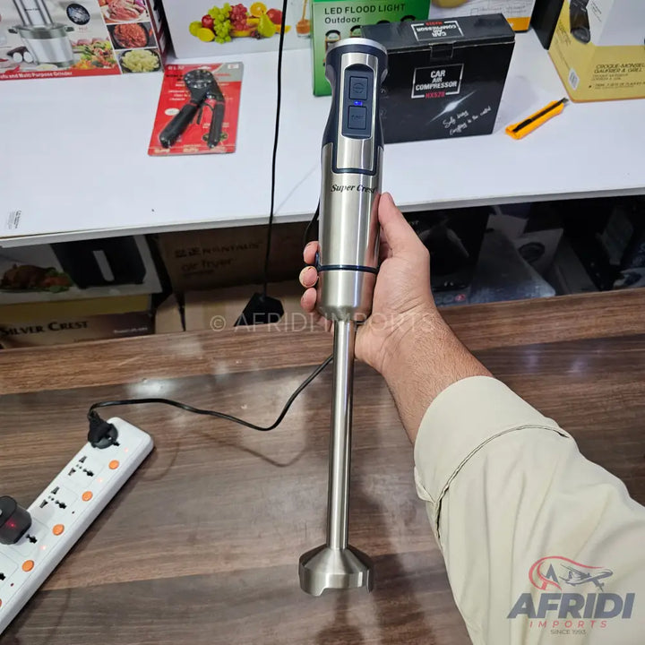 A silver, handheld immersion blender with a black control panel and power cord.