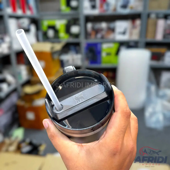 A stainless steel travel mug with a black lid and a clear straw.