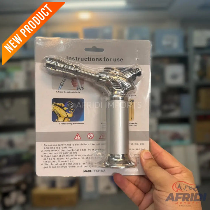 A chrome-plated butane torch in blister packaging.