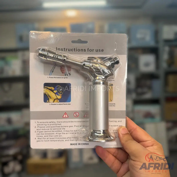 A chrome-plated butane torch in blister packaging.