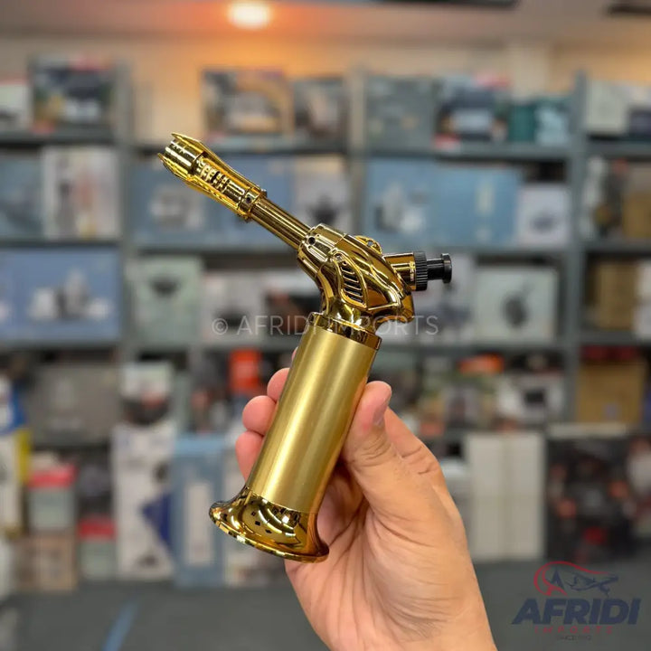 A gold-colored butane torch with a trigger ignition and a stable base.