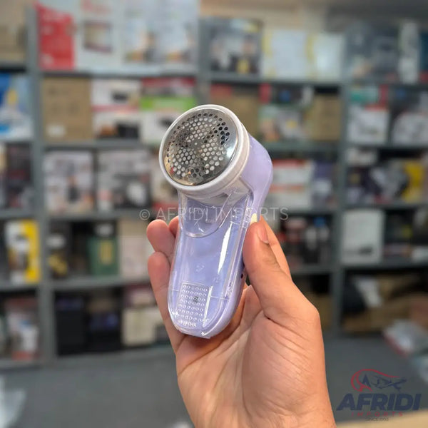 A handheld, purple fabric shaver with a metallic mesh head.