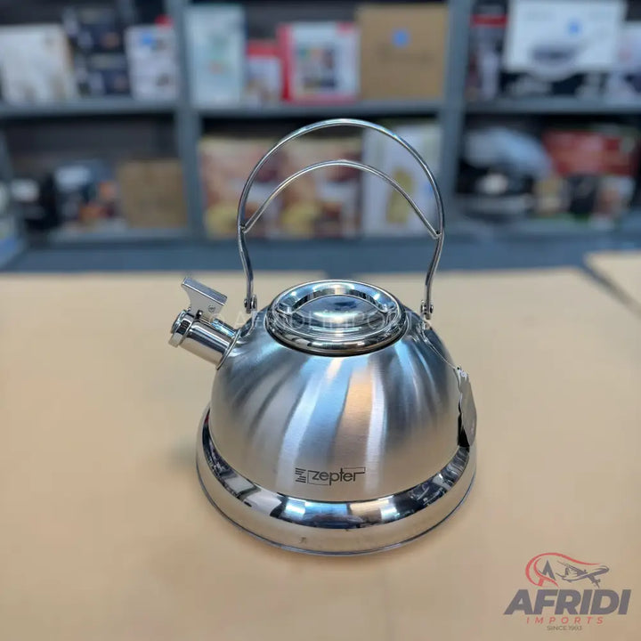 A shiny, stainless steel stovetop kettle with a whistle spout and a metal swing handle.