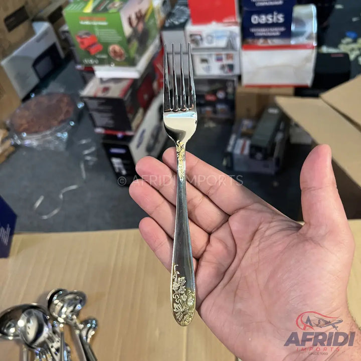 Silver-colored metal fork with a gold floral design on the handle.